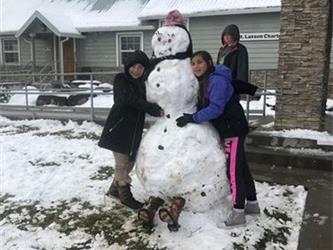students posing with snowman